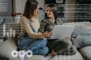 woman and her daughter sit on sofa looking at laptop computer